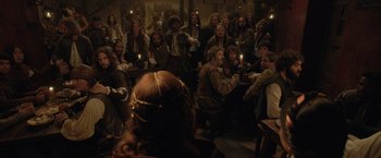 Movie still from “Rosaline” (2022), directed by Karen Maine – A group of people sitting around a table with candles; Wide shot, High angle