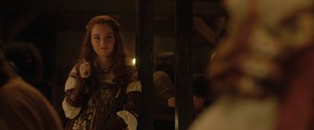 Movie still from “Rosaline” (2022), directed by Karen Maine – A young woman in a medieval dress looking at herself in a mirror; Medium shot, Over the shoulder angle