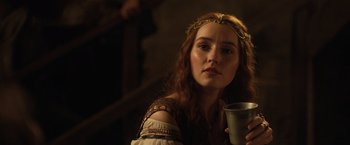 Movie still from “Rosaline” (2022), directed by Karen Maine – A beautiful young lady with red hair holding a cup; Close Up shot, Over the shoulder angle
