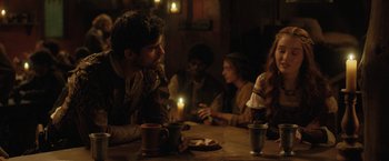 Movie still from “Rosaline” (2022), directed by Karen Maine – A group of people sitting at a table with candles; Medium shot, Over the shoulder angle
