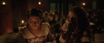 Movie still from “Rosaline” (2022), directed by Karen Maine – Two women in medieval garb are drinking from cups; Close Up shot, Over the shoulder angle