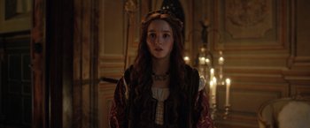 Movie still from “Rosaline” (2022), directed by Karen Maine – A young woman in medieval garb stands in front of a wall; Close Up shot, Over the shoulder angle