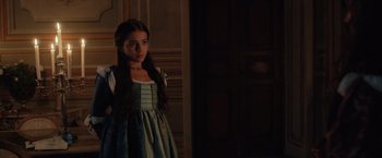Movie still from “Rosaline” (2022), directed by Karen Maine – A young girl in a medieval dress standing in front of a door; Medium shot, Over the shoulder angle
