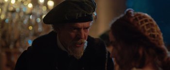 Movie still from “Rosaline” (2022), directed by Karen Maine – An old man with a beard wearing a hat; Close Up shot, Over the shoulder angle