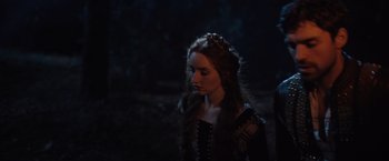 Movie still from “Rosaline” (2022), directed by Karen Maine – A woman in a black dress is standing in the dark; Close Up shot, Over the shoulder angle