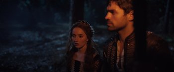 Movie still from “Rosaline” (2022), directed by Karen Maine – A woman and a man standing next to each other in a forest; Close Up shot, Over the shoulder angle