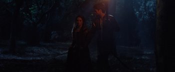 Movie still from “Rosaline” (2022), directed by Karen Maine – A man and a woman standing next to each other in the dark; Medium shot, Over the shoulder angle