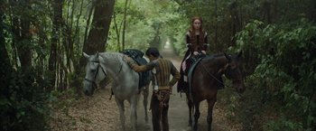 Movie still from “Rosaline” (2022), directed by Karen Maine – A man and a woman on horses on a path; Wide shot, Over the shoulder angle