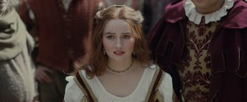 Movie still from “Rosaline” (2022), directed by Karen Maine – A young woman in medieval garb looking at the camera; Close Up shot, Over the shoulder angle