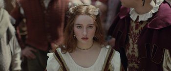 Movie still from “Rosaline” (2022), directed by Karen Maine – A young woman in medieval garb looking at the camera; Close Up shot, Over the shoulder angle