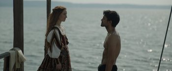 Movie still from “Rosaline” (2022), directed by Karen Maine – A man and a woman standing next to a body of water; Medium shot, Over the shoulder angle