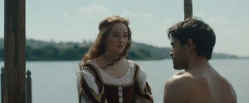 Movie still from “Rosaline” (2022), directed by Karen Maine – A young woman in a renaissance dress talking to a young man; Medium shot, Over the shoulder angle
