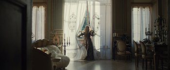 Movie still from “Rosaline” (2022), directed by Karen Maine – A woman dressed as a princess standing in front of a window; Wide shot, Over the shoulder angle