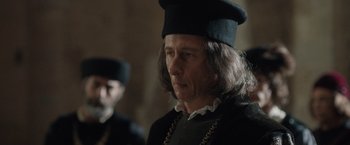 Movie still from “Rosaline” (2022), directed by Karen Maine – A man wearing a black hat and a chain around his neck; Close Up shot, Over the shoulder angle