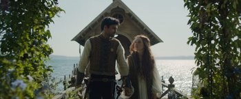 Movie still from “Rosaline” (2022), directed by Karen Maine – A man and a woman standing next to each other holding hands; Medium shot, Over the shoulder angle