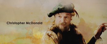 Movie still from “Rosaline” (2022), directed by Karen Maine – A man with a beard wearing a green hat; Medium shot, High angle