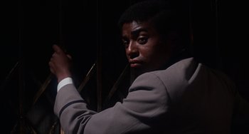 Movie still from “Rosemary's Baby” (1968), directed by Roman Polanski – A man in a gray suit is holding a cane; Close Up shot, Low angle