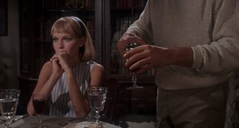 Movie still from “Rosemary's Baby” (1968), directed by Roman Polanski – A woman sitting at a table with a man pouring wine into a wine glass; Medium shot, Over the shoulder angle