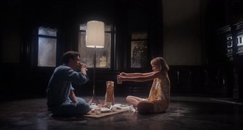 Movie still from “Rosemary's Baby” (1968), directed by Roman Polanski – A man and a woman sitting on the floor eating food; Wide shot, Low angle