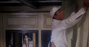 Movie still from “Rosemary's Baby” (1968), directed by Roman Polanski – A man in white shirt and hat painting a wall; Medium shot, Low angle