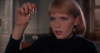 Movie still from “Rosemary's Baby” (1968), directed by Roman Polanski – A young woman holding a rosary in her hand; Close Up shot, High angle