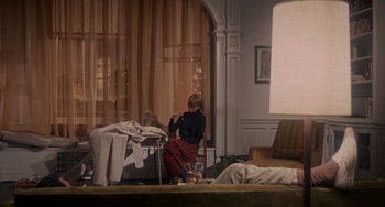 Movie still from “Rosemary's Baby” (1968), directed by Roman Polanski – A woman sitting on a chair next to a man sleeping; Wide shot, High angle