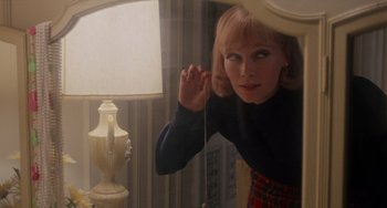 Movie still from “Rosemary's Baby” (1968), directed by Roman Polanski – A woman is looking in the mirror in front of a lamp; Close Up shot, Over the shoulder angle