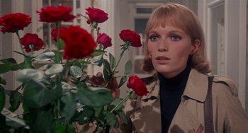 Movie still from “Rosemary's Baby” (1968), directed by Roman Polanski – A woman standing next to a bunch of red roses; Close Up shot, Low angle