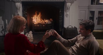 Movie still from “Rosemary's Baby” (1968), directed by Roman Polanski – A man and a woman sitting in front of a fireplace; Medium shot, High angle