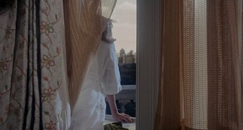 Movie still from “Rosemary's Baby” (1968), directed by Roman Polanski – A woman standing in front of a window looking outside; Medium shot, High angle