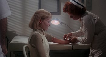 Movie still from “Rosemary's Baby” (1968), directed by Roman Polanski – A woman getting her arm examined by a nurse; Medium shot, High angle