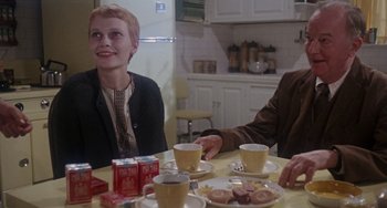 Movie still from “Rosemary's Baby” (1968), directed by Roman Polanski – A woman sitting at a table with two men; Medium shot, Over the shoulder angle