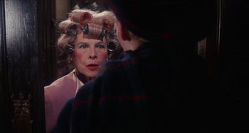 Movie still from “Rosemary's Baby” (1968), directed by Roman Polanski – A woman with curlers in her hair looking in a mirror; Close Up shot, Over the shoulder angle