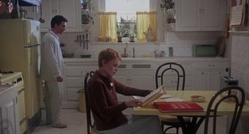 Movie still from “Rosemary's Baby” (1968), directed by Roman Polanski – A boy sitting at a kitchen table reading a book; Wide shot, Over the shoulder angle