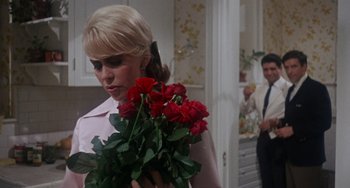 Movie still from “Rosemary's Baby” (1968), directed by Roman Polanski – A woman holding a bouquet of red roses in her hands; Medium shot, Over the shoulder angle