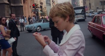 Movie still from “Rosemary's Baby” (1968), directed by Roman Polanski – A young woman is looking at her cell phone while walking down the street; Medium shot, Low angle