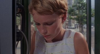 Movie still from “Rosemary's Baby” (1968), directed by Roman Polanski – A young woman with short blonde hair looking down at her face; Close Up shot, High angle