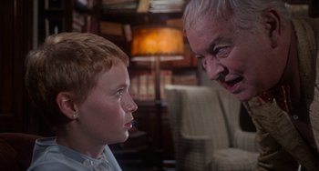 Movie still from “Rosemary's Baby” (1968), directed by Roman Polanski – An older man talking to a young boy in front of a chair; Close Up shot, Over the shoulder angle
