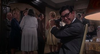 Movie still from “Rosemary's Baby” (1968), directed by Roman Polanski – A man in a suit and tie holding a hair dryer; Medium shot, Low angle