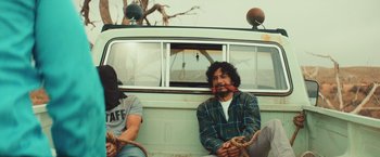 Movie still from “Run & Gun” (2022), directed by Christopher Borrelli – Two men sitting in the back of a van; Medium shot, Low angle