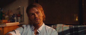 Movie still from “Run & Gun” (2022), directed by Christopher Borrelli – A person with long hair; Close Up shot, Over the shoulder angle