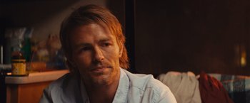 Movie still from “Run & Gun” (2022), directed by Christopher Borrelli – A person with long hair; Close Up shot, Over the shoulder angle