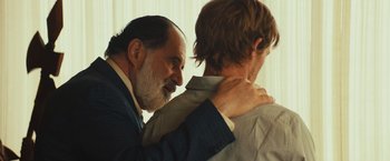 Movie still from “Run & Gun” (2022), directed by Christopher Borrelli – A man and a man in a suit and tie; Close Up shot, Over the shoulder angle