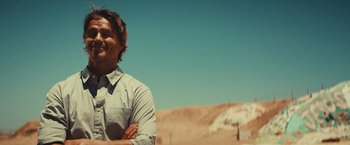 Movie still from “Run & Gun” (2022), directed by Christopher Borrelli – A man standing in the middle of the desert; Medium shot, Low angle