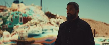 Movie still from “Run & Gun” (2022), directed by Christopher Borrelli – A man with a beard standing in front of a painting; Medium shot, Over the shoulder angle