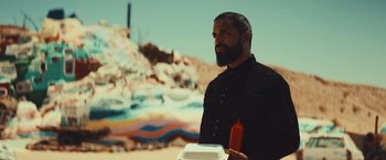 Movie still from “Run & Gun” (2022), directed by Christopher Borrelli – A man holding a hot dog bun and ketchup bottle; Medium shot, Low angle