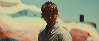 Movie still from “Run & Gun” (2022), directed by Christopher Borrelli – A person wearing a white shirt; Close Up shot, Low angle