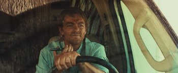Movie still from “Run & Gun” (2022), directed by Christopher Borrelli – A person in a car holding a steering wheel; Close Up shot, Over the shoulder angle