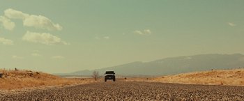 Movie still from “Run & Gun” (2022), directed by Christopher Borrelli – A car driving down a dirt road in the desert; Extreme Wide shot, Low angle