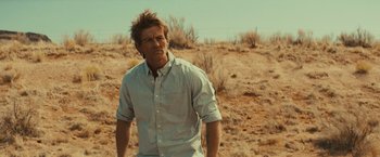 Movie still from “Run & Gun” (2022), directed by Christopher Borrelli – A man standing in the middle of the desert; Medium shot, Over the shoulder angle